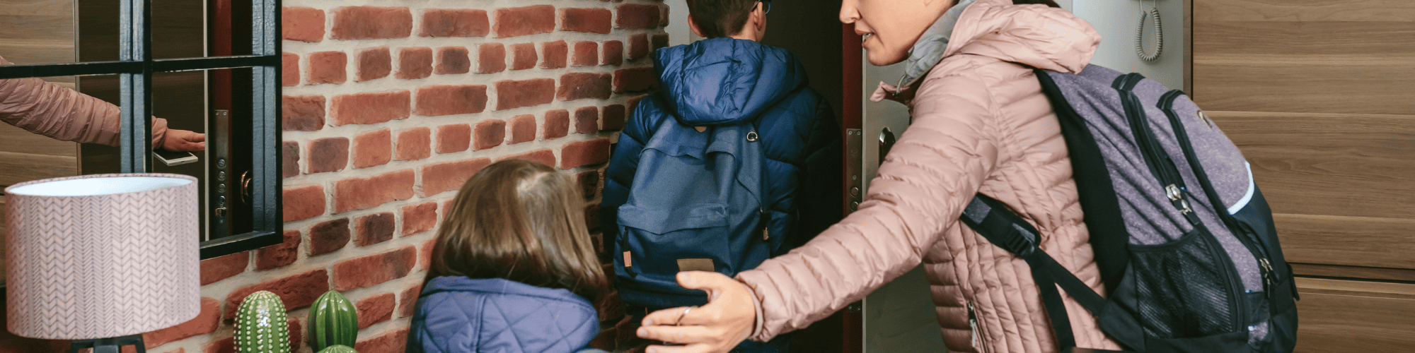 A single mother helping her two children out the door of their apartment for school